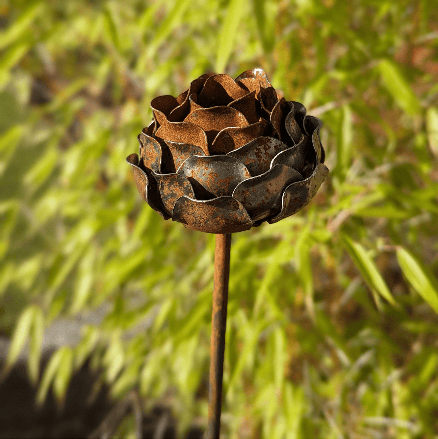 Handcrafted rusted metal peony garden stake with layered petals and sculptural charm, styled in a heritage-inspired UK garden border as a timeless outdoor ornament