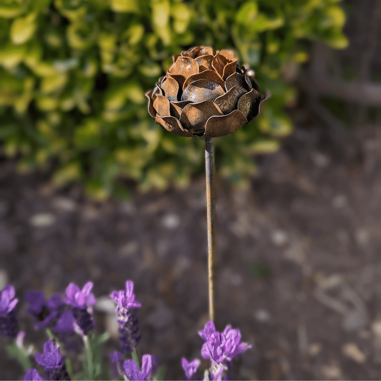 Handcrafted rusted metal peony garden stake with layered petals and sculptural detail, styled in a heritage-inspired UK garden border