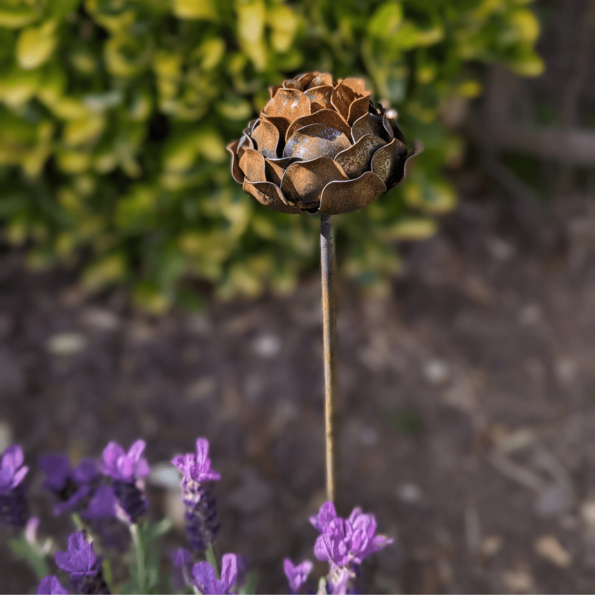 Handcrafted rusted metal peony garden stake with layered petals and sculptural detail, styled in a heritage-inspired UK garden border