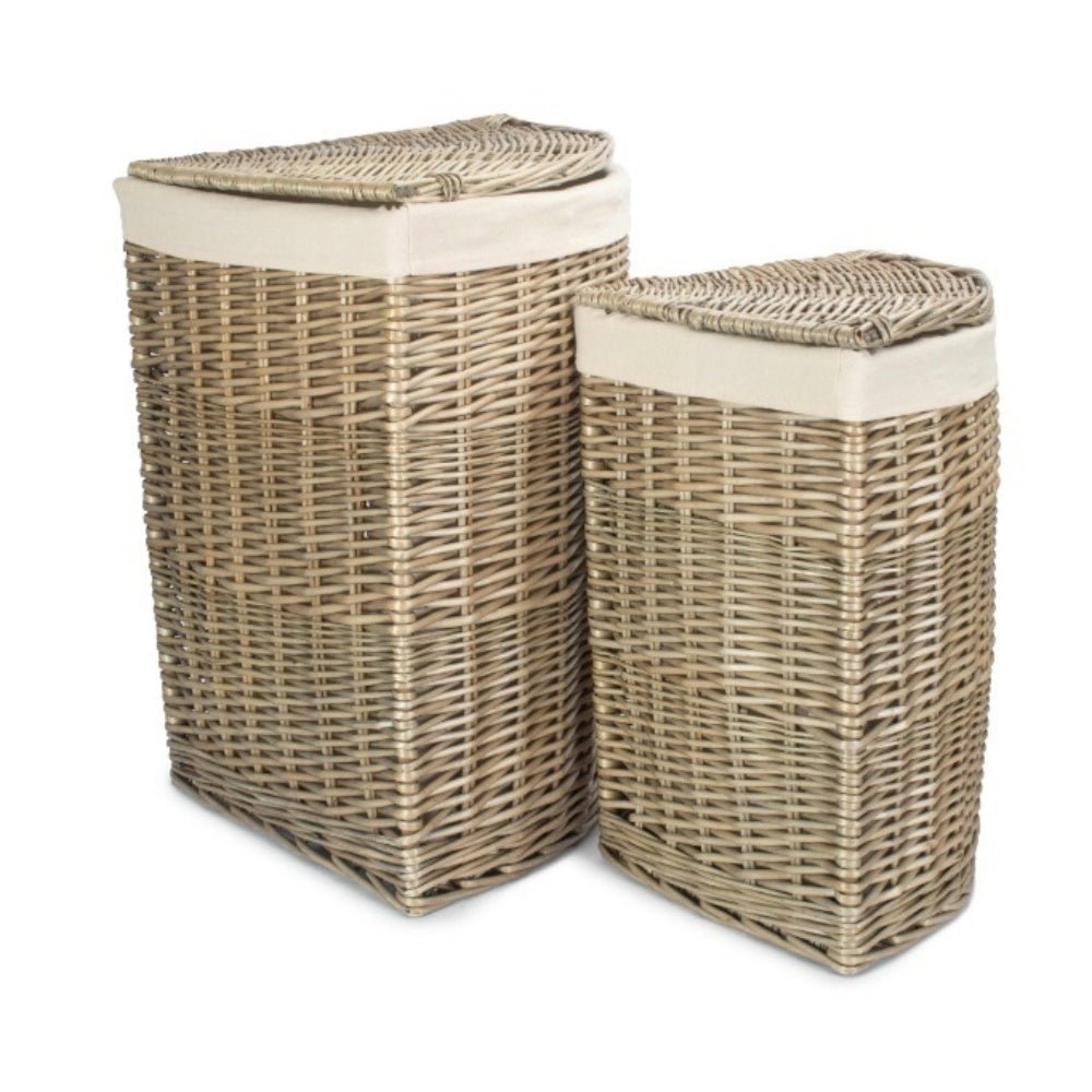 Corner-shaped antique wash willow laundry basket with removable white cotton lining, styled in a softly lit hallway.