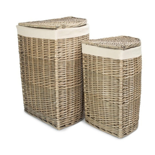Corner-shaped antique wash willow laundry basket with removable white cotton lining, styled in a softly lit hallway.