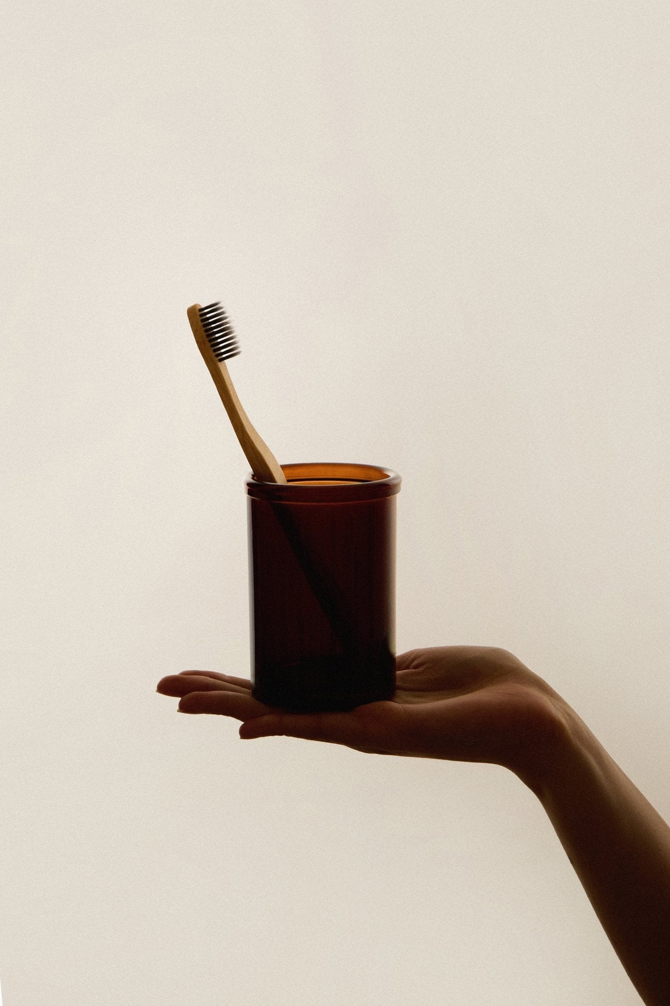 The Wetherby Amber Glass Toothbrush Holder – vintage-style amber glass cup shown with toothbrush inside, styled beside a basin for timeless bathroom rituals.