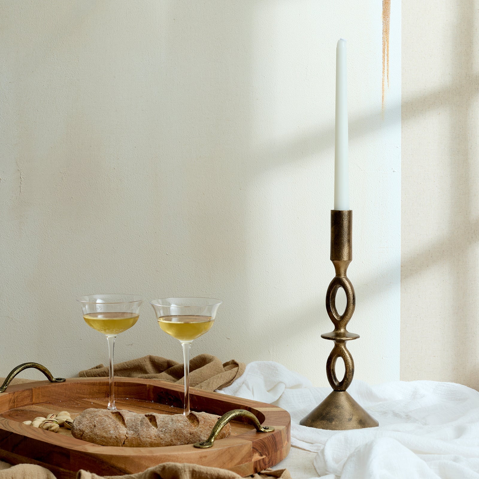 The Branlow Hearth Tray styled with bread and wine beside a brass candle holder—oval fir wood tray evoking rustic hosting and soulful evening rituals