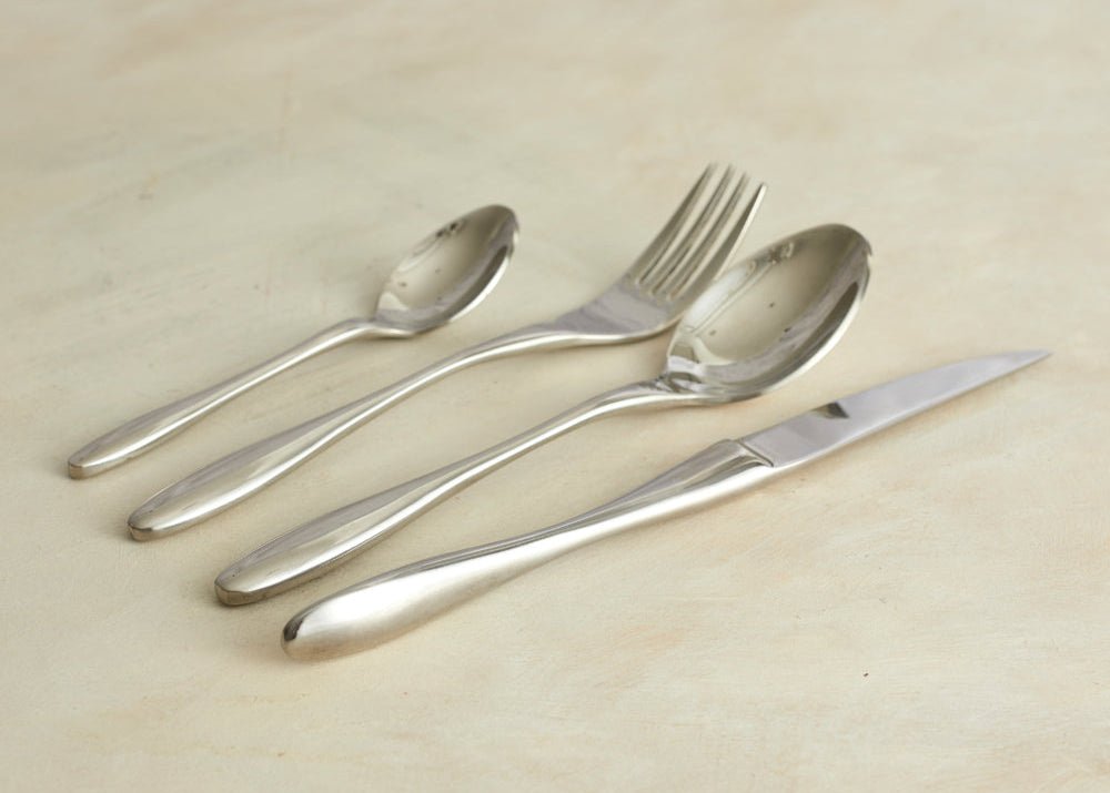 Branston silver stainless steel cutlery set arranged on a natural wood tabletop—evokes timeless hosting, rustic charm, and soulful countryside dining.