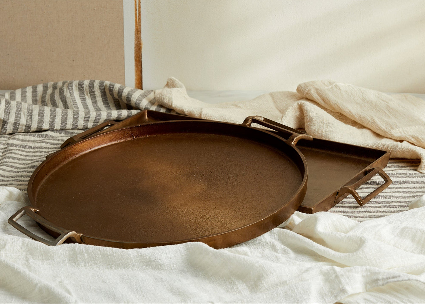 Brontë Bronze Round Tray stacked on Rectangular Tray – warm bronze aluminium, handcrafted finish, layered styling for soulful serveware and display
