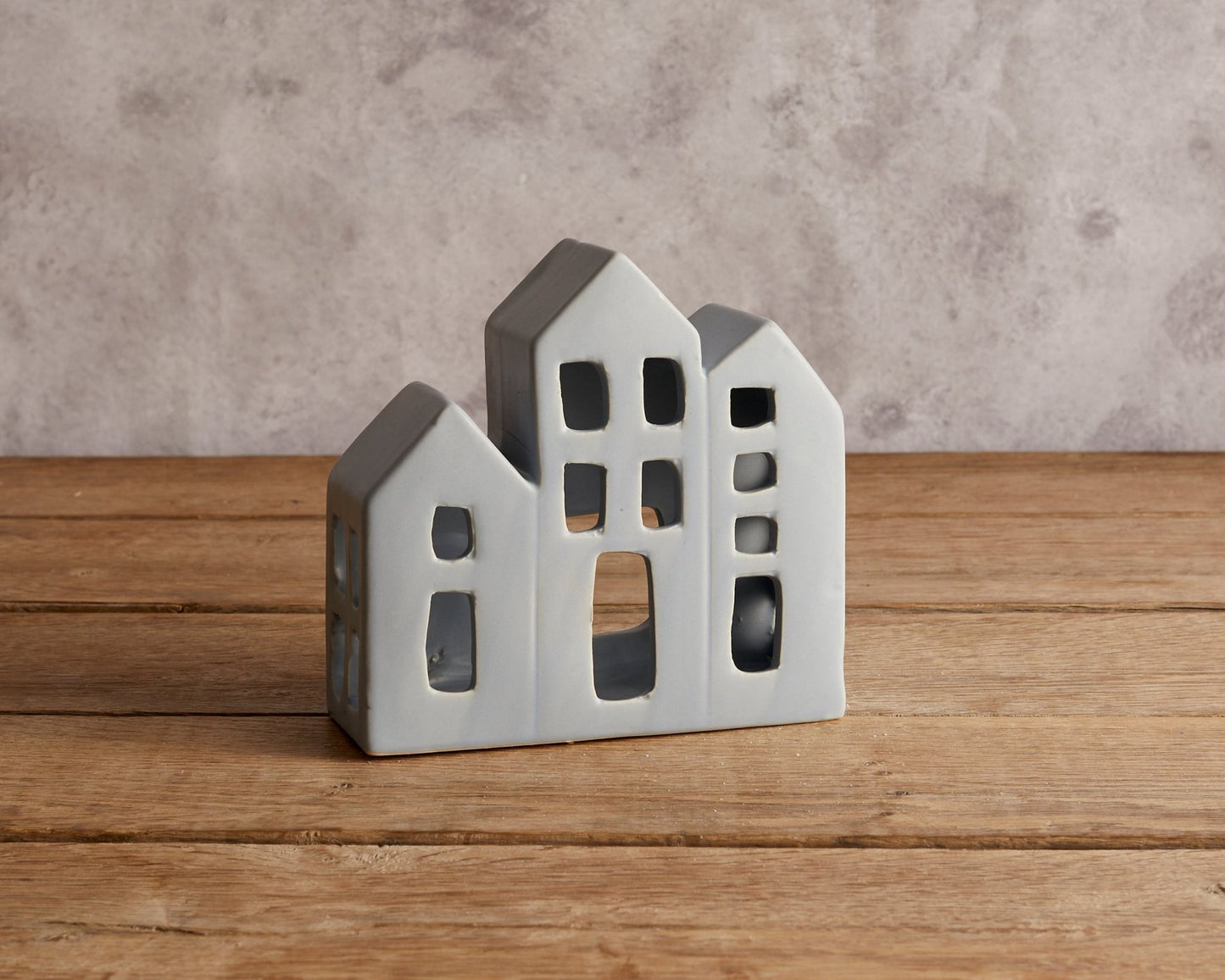 Ceramic candle house tealight holder Wintersbury Festive displayed on wooden tabletop with warm glow