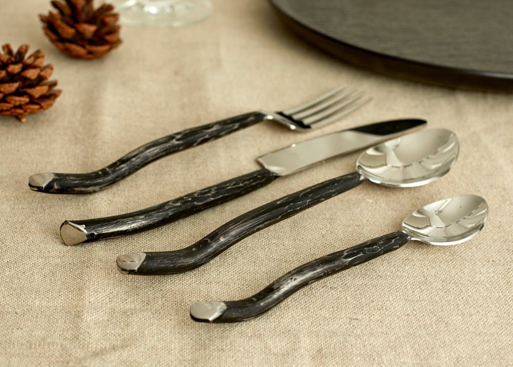 Close-up of Elmswell silver cutlery set on natural linen cloth with scattered pinecones—evokes festive warmth, rustic charm, and soulful seasonal hosting.
