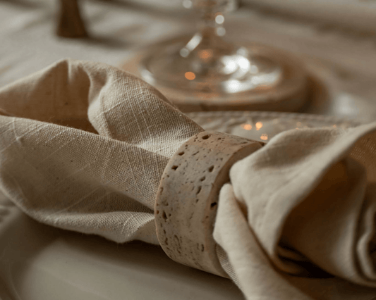 Set of four travertine napkin rings with soft veining and polished finish, styled on a rustic table for timeless gatherings and countryside-inspired charm.