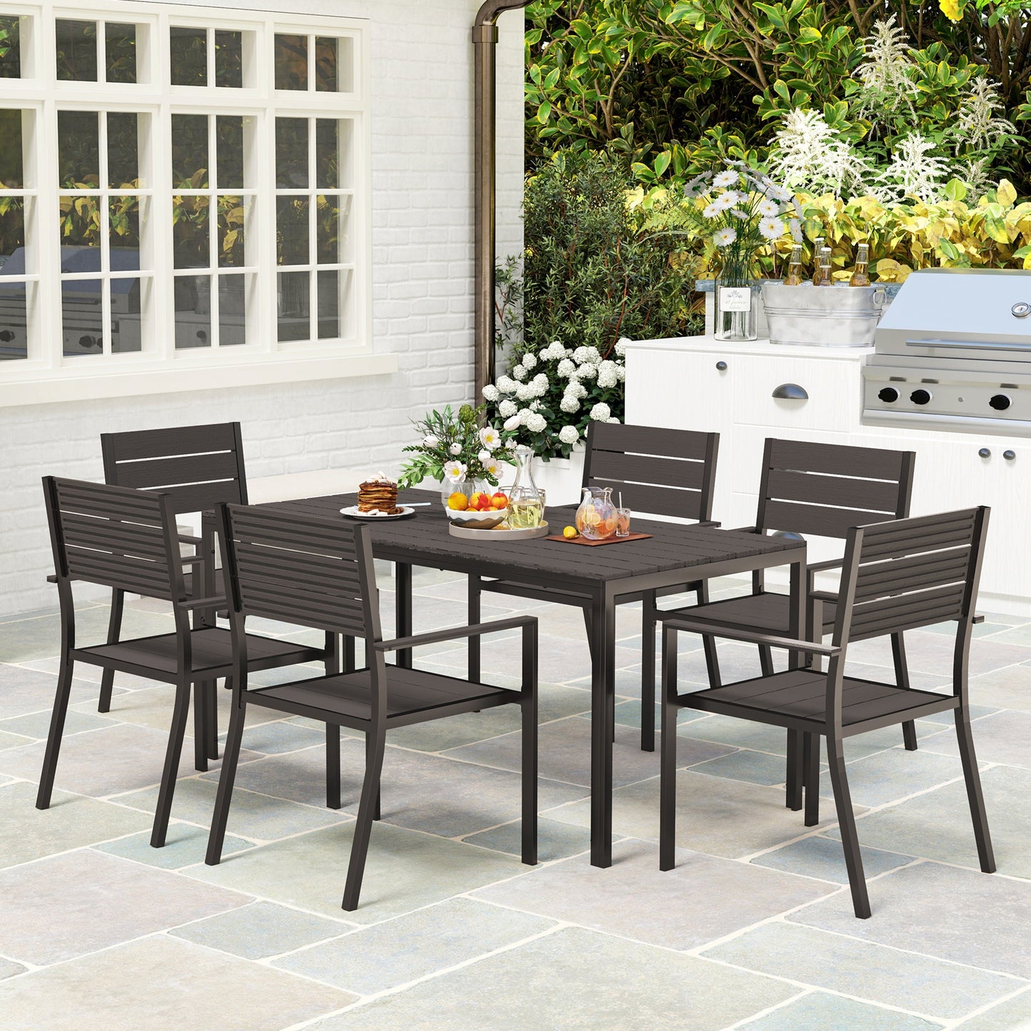 The Hardwick Gathering 7-piece garden dining set with dark brown HDPE slatted table and six stackable steel-frame chairs, styled on a stone patio for timeless outdoor hosting