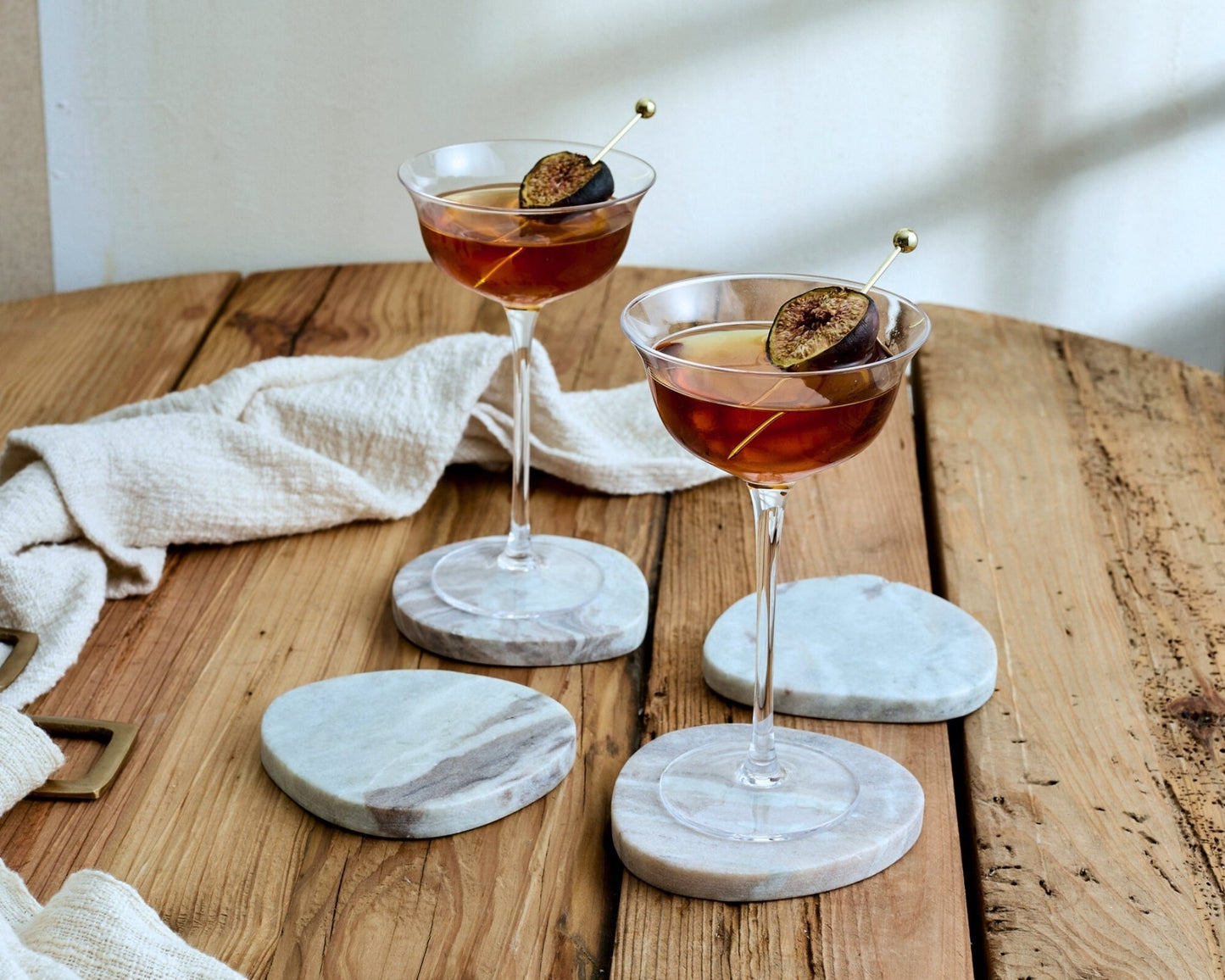 Set of natural marble coasters with visible veining and irregular shape, styled for countryside homes and artisan interiors.