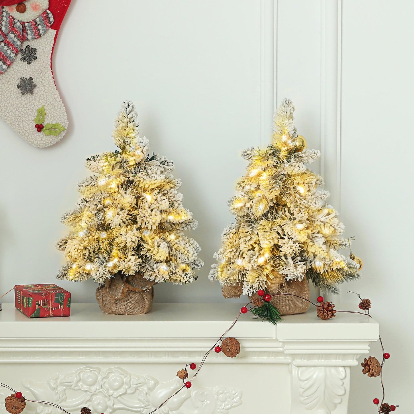 Set of two 1.5ft snow-flocked tabletop Christmas trees with warm white LED lights. Miniature artificial firs with linen-wrapped bases and rustic styling.
