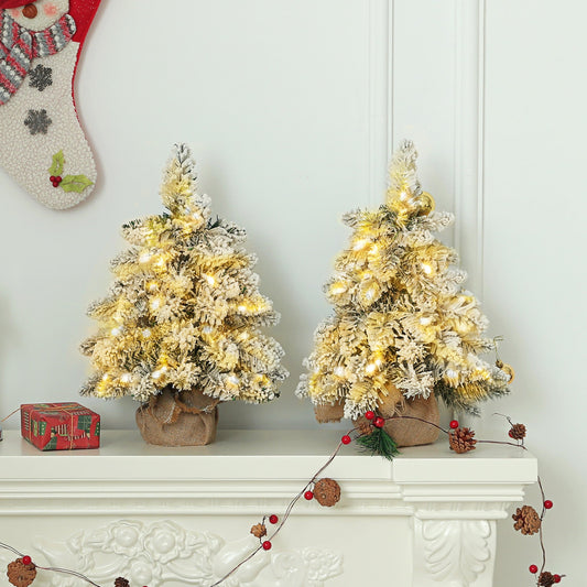 Set of two 1.5ft snow-flocked tabletop Christmas trees with warm white LED lights. Miniature artificial firs with linen-wrapped bases and rustic styling.