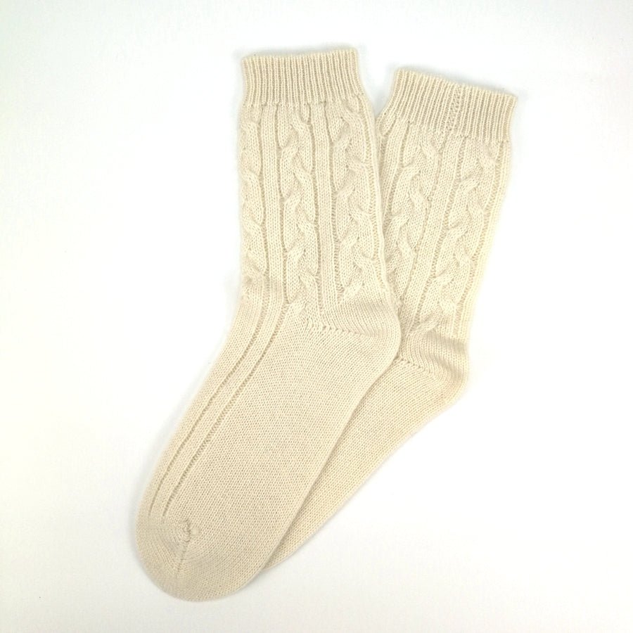 Soft cream cable knit cashmere sleep socks shown flat on a plain white background in cozy countryside style.