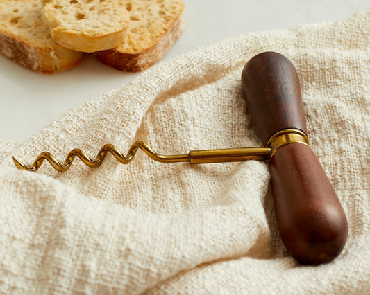 Close-up of The Thistle Cellar Key corkscrew showing smooth acacia wood handle and brushed steel body—heritage wine opener with rustic bar styling