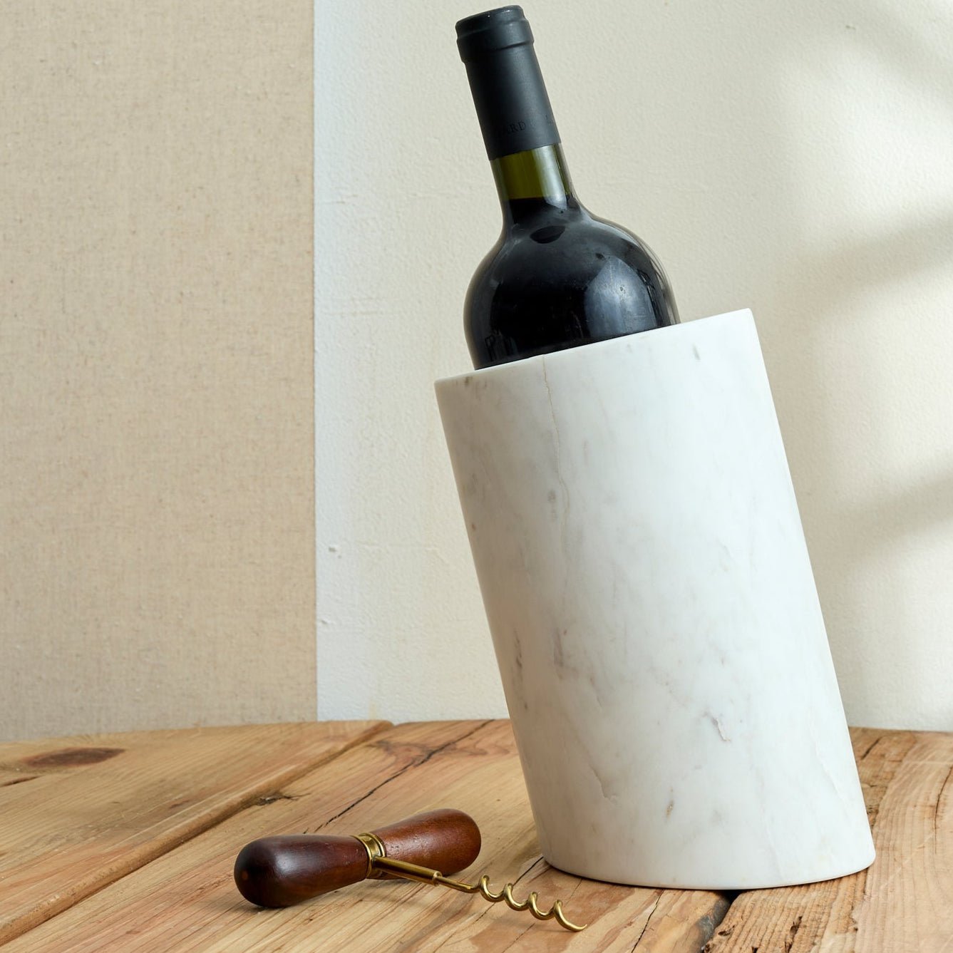 The Thistle Cellar Key corkscrew placed beside a rustic wine bottle holder—acacia and steel opener styled for heritage bar rituals and soulful hosting