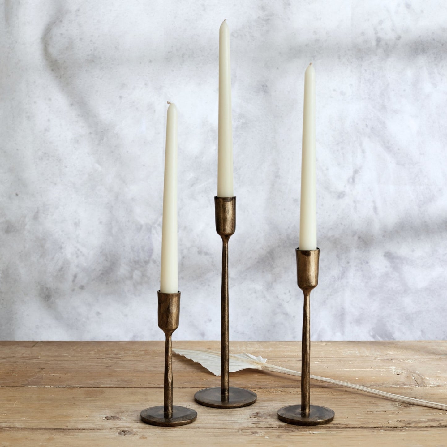 Weldon Iron Candle Holder Set – hand-forged antique brass finish, styled on rustic wooden table for soulful glow and countryside-inspired warmth