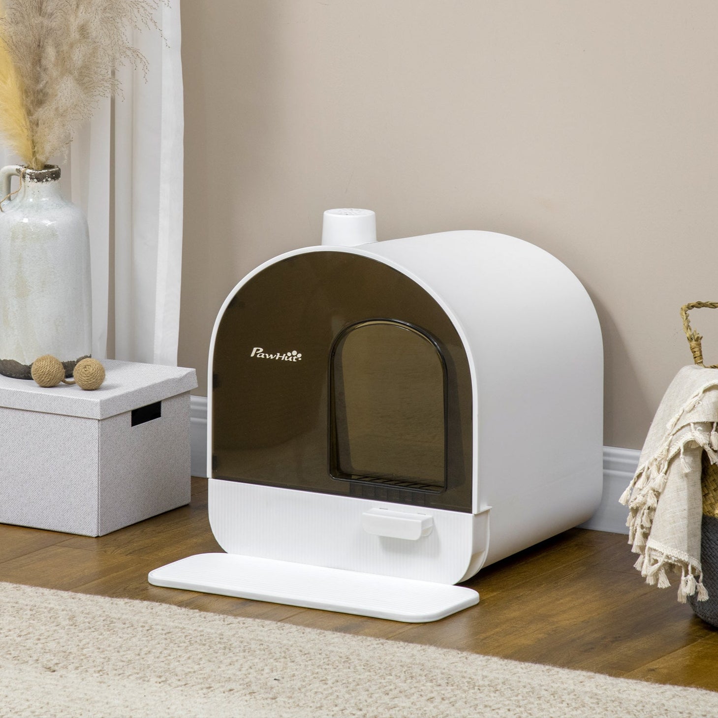The Willow Whiskers Hooded Cat Litter Box – shown in a cosy interior scene on a wooden floor beside a woven basket and neutral-toned rug, blending discreet feline comfort with heritage-inspired home styling
