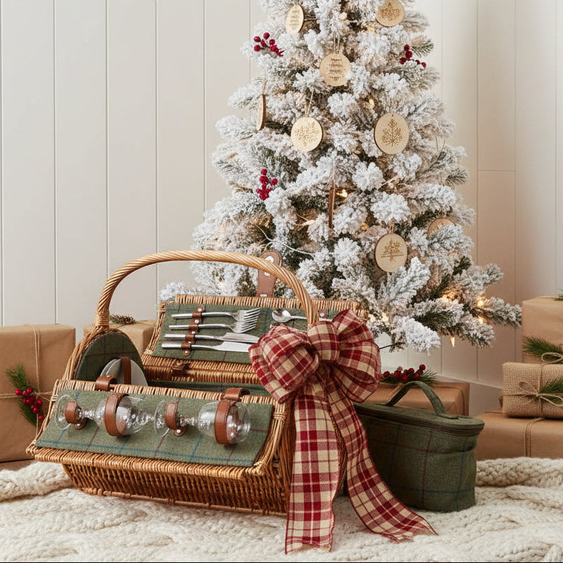 Two person green tweed wicker picnic basket fully fitted under Christmas tree with rustic bow ready to gift
