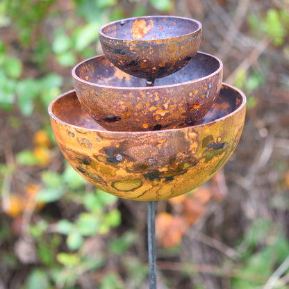 Rustic metal bowl fountain with a blurred natural background