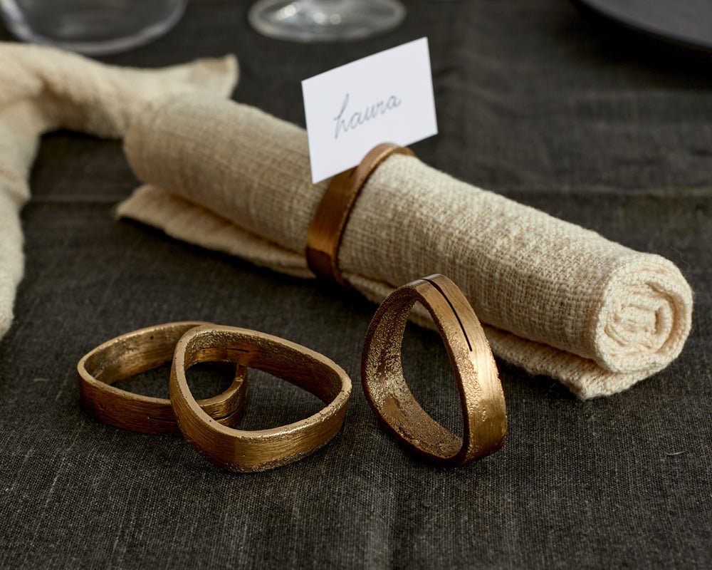 Agnes brass napkin rings set of 4 handcrafted table accents on table with napkin and place name
