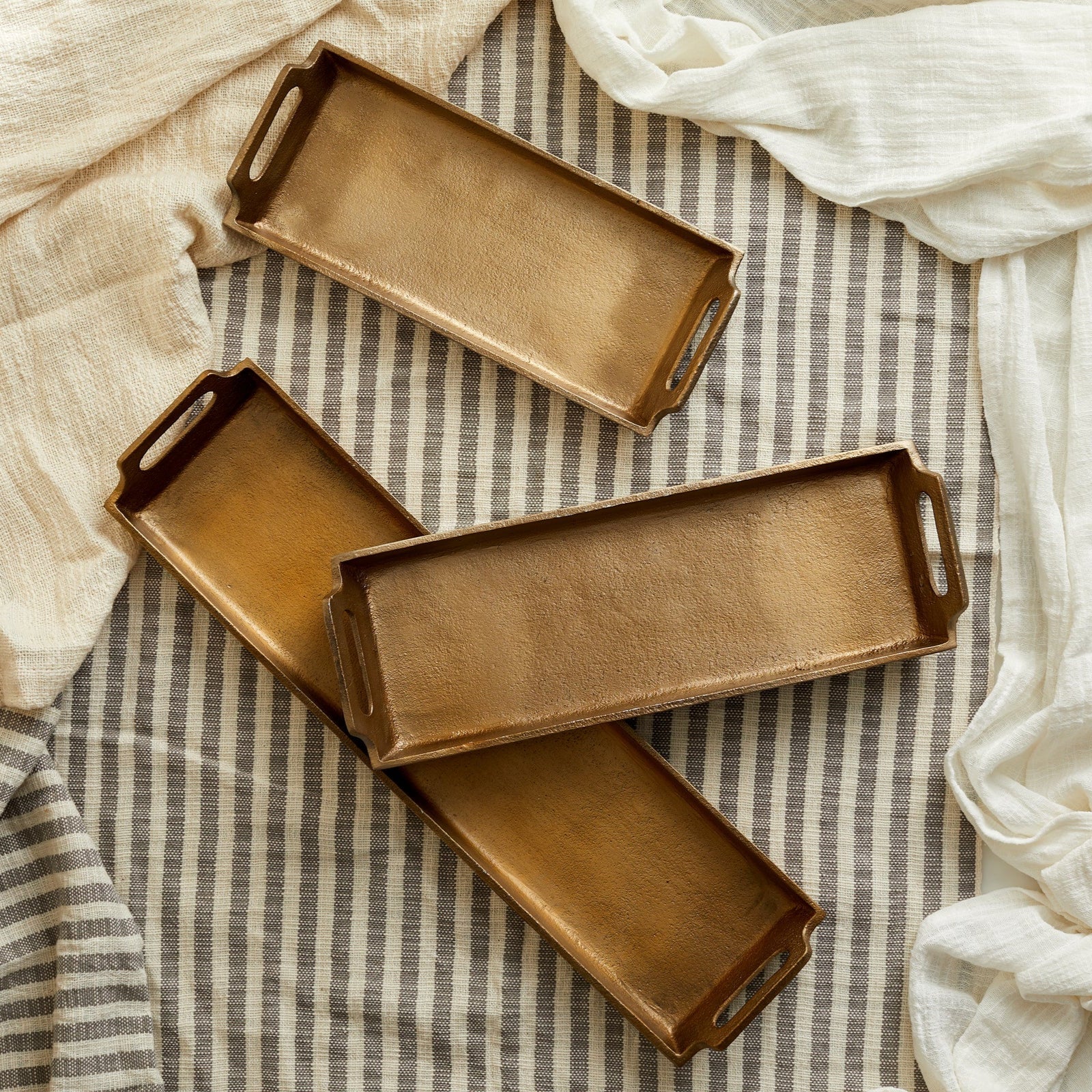 Alderley Gold Tray – brushed gold aluminium in three sizes, styled on soft linen cloth for timeless hosting, rustic elegance, and soulful presentation
