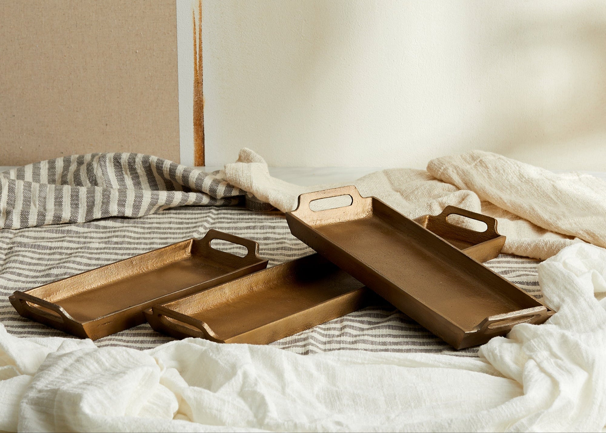 Alderley Gold Trays – brushed gold aluminium in small, medium, and large sizes, styled on linen-clad tabletop for soulful hosting and rustic elegance