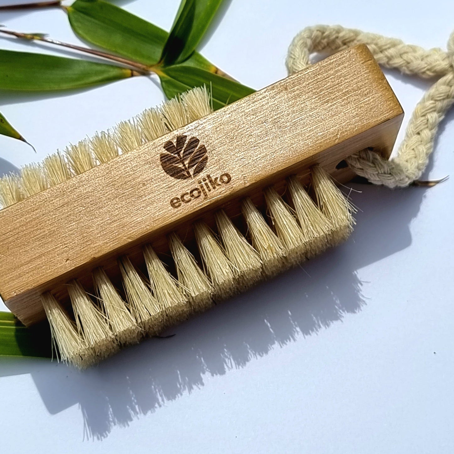 Close-up of bamboo nail brush with natural plant-based bristles and rustic styling on textured surface