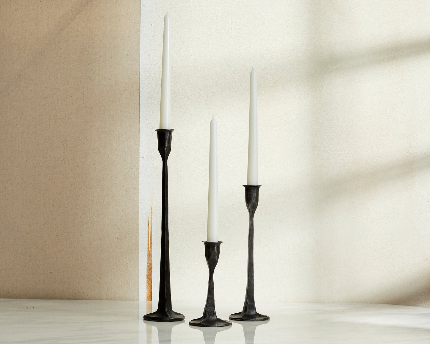 Bloomsbury Iron Black Candle Holder Set of 3 displayed on a table with neutral wall behind