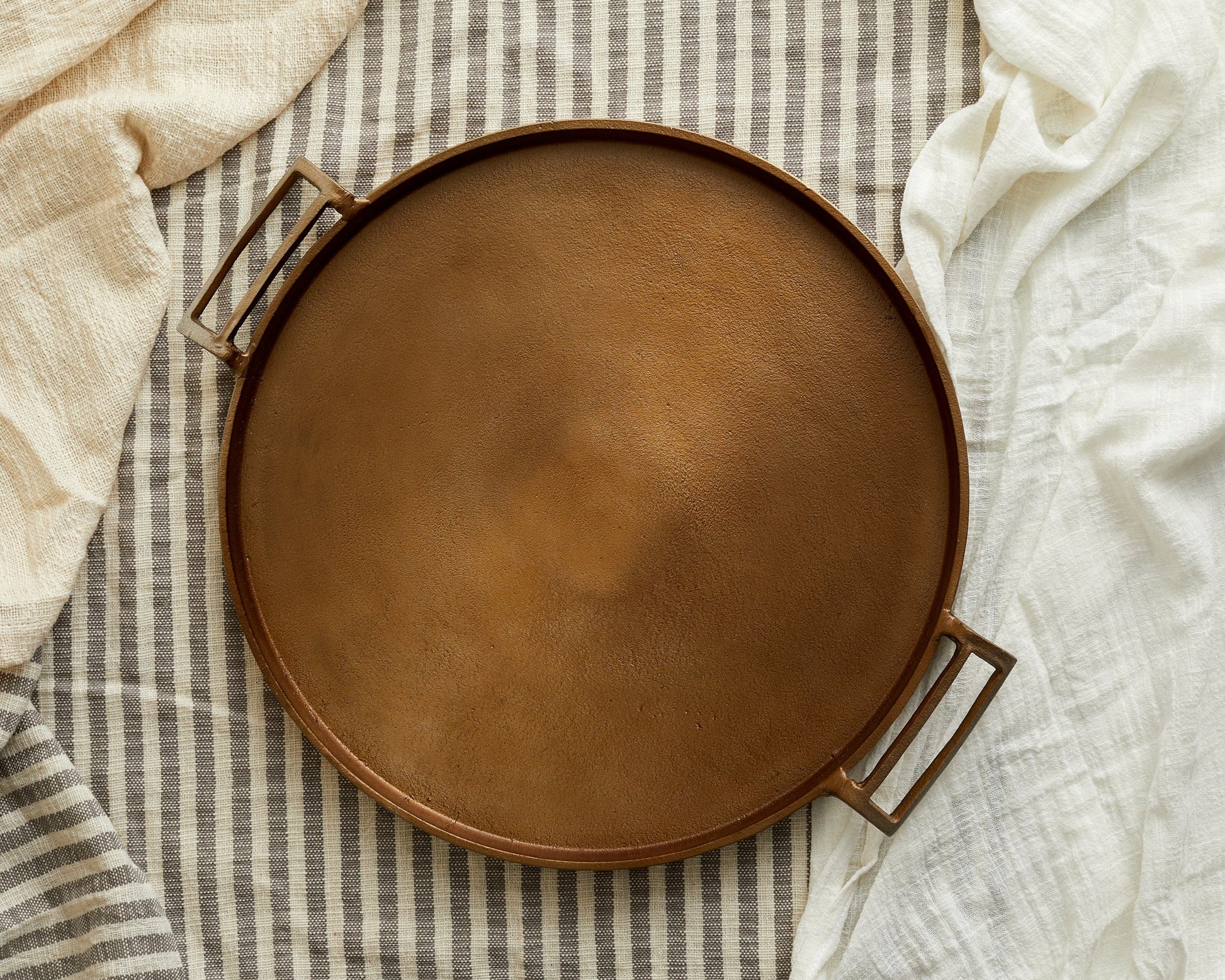 Brontë bronze round hand finished serving tray styled on top of linens
