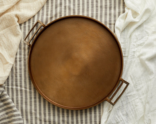 Brontë bronze round hand finished serving tray styled on top of linens
