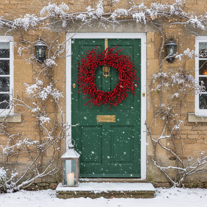 Red berry Christmas wreath on green country door with frosted ivy and winter foliage