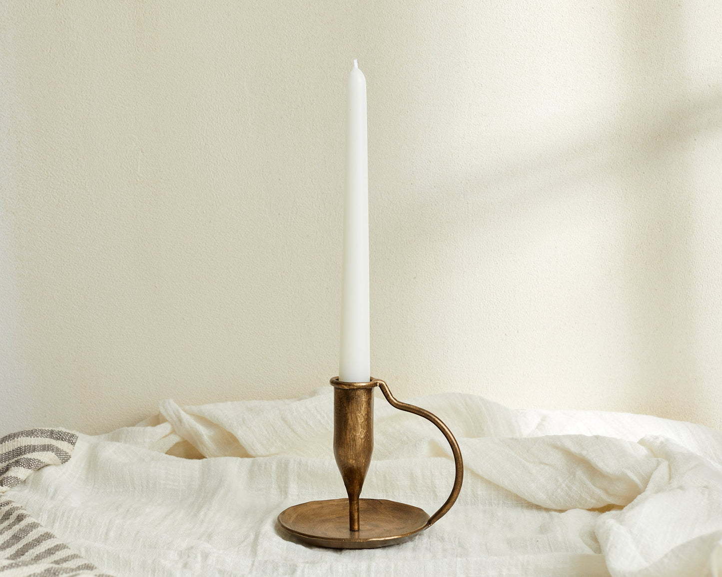 Iron candle holder brushed gold Ashbourne Hearth styled with tapered candle on linen cloth

