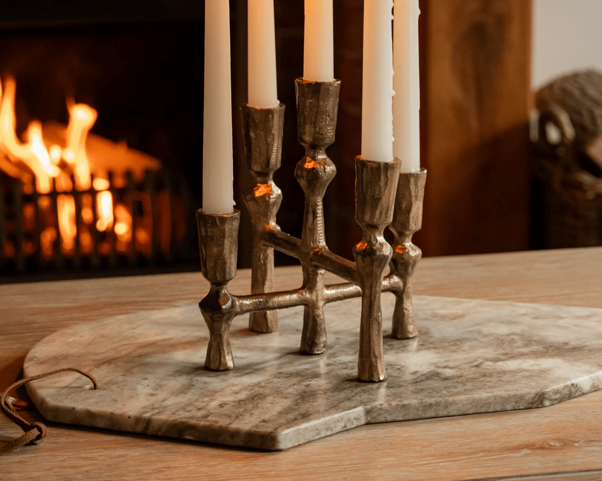 Pembroke iron candelabra five arm candleholder styled on coffee table with open fire in background

