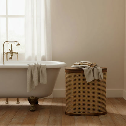Rattan storage stool with lid in bathroom beside rolltop bath on wooden floor
