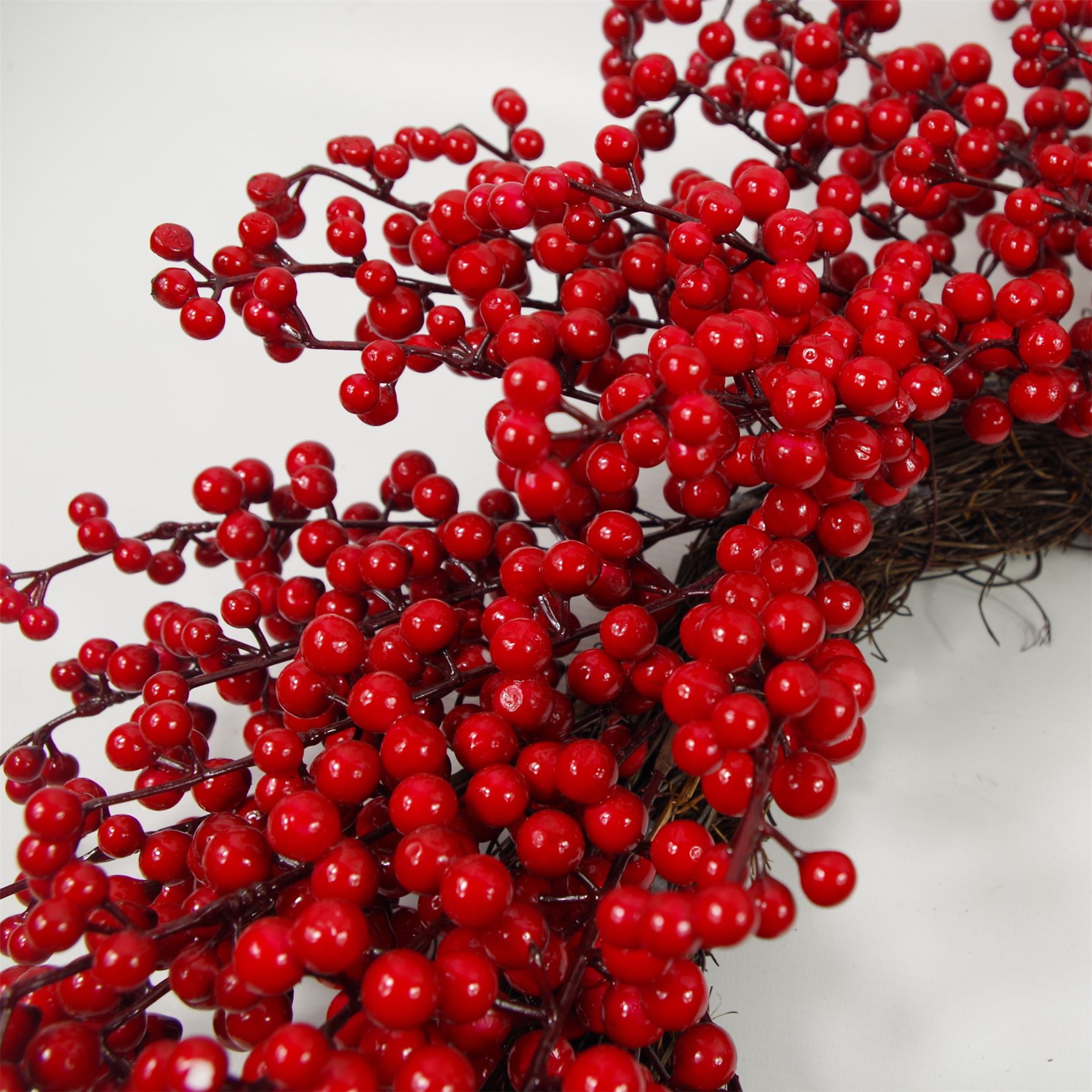 Close-up of glossy red berries and green leaves on Christmas wreath with natural texture