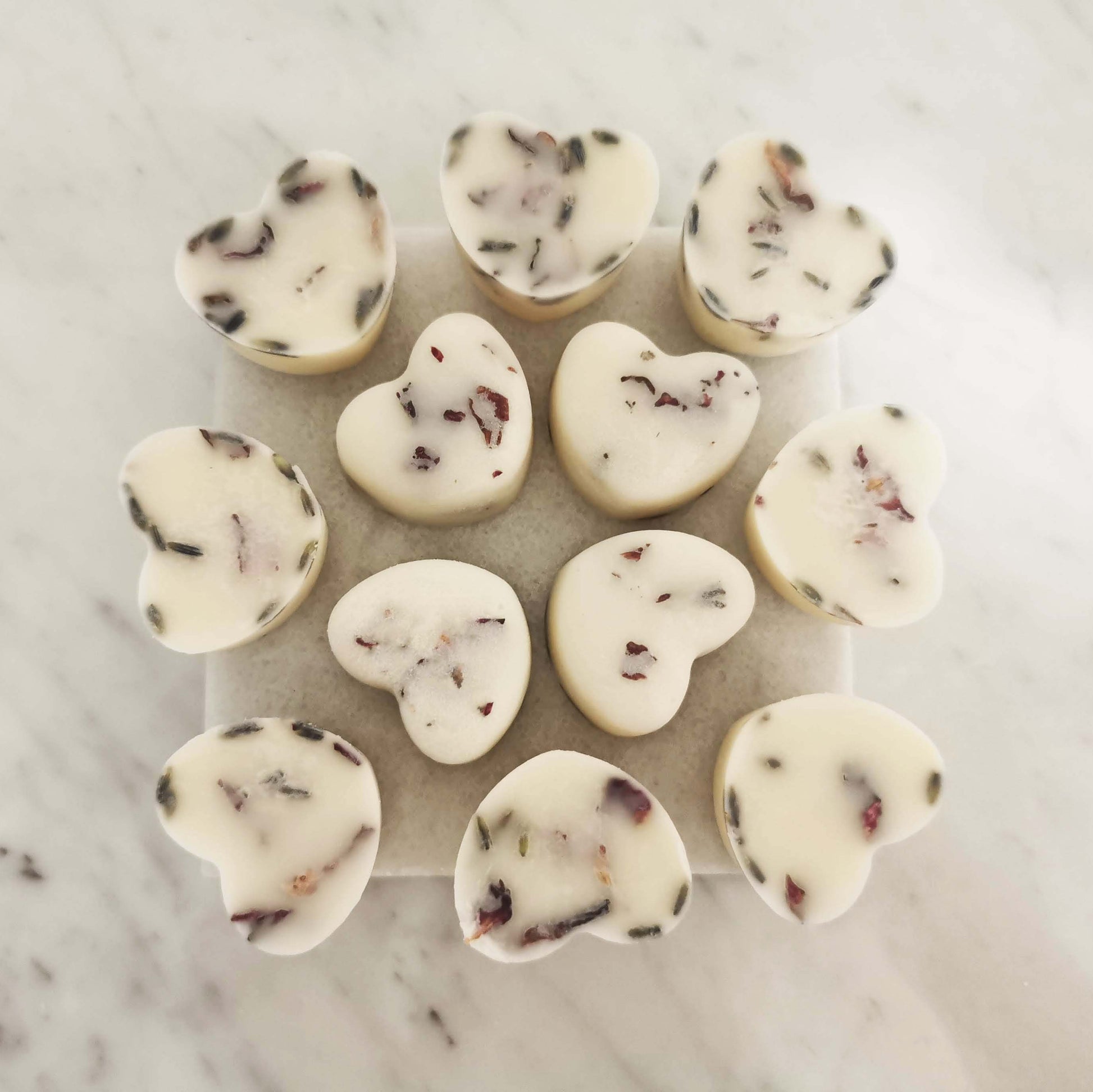 Close view of rose geranium lavender ylang ylang vetiver wax melts with rose petals and essential oils
