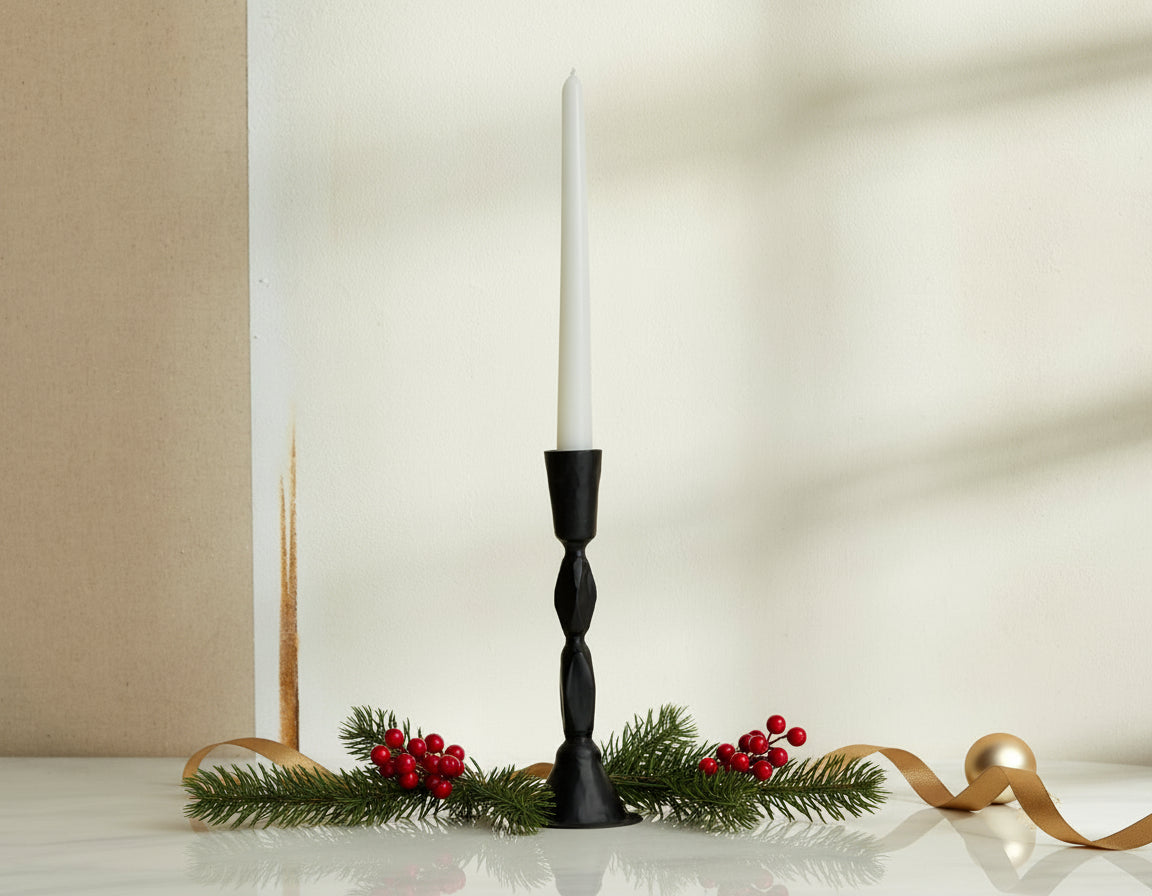 Sculptural black candle holder in blackened brass decorated with festive sprig, ribbon and baubles
