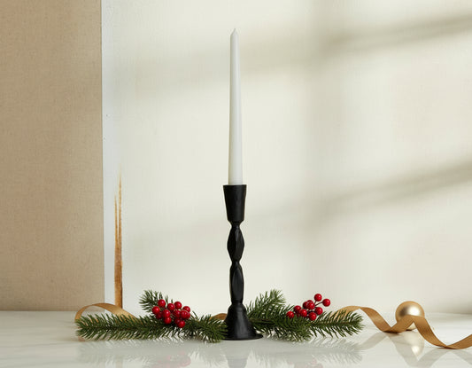 Sculptural black candle holder in blackened brass decorated with festive sprig, ribbon and baubles