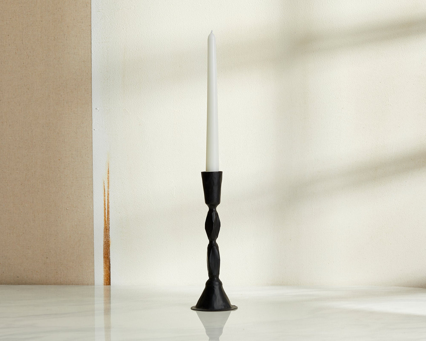 Sculptural black candle holder in blackened brass displayed on neutral background