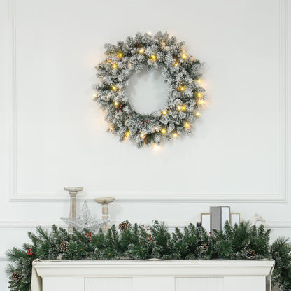 Snowy 60-inch Christmas wreath with pinecones, berries & warm LED lights styled above a festive mantle — lifelike branches in a cosy countryside setting.