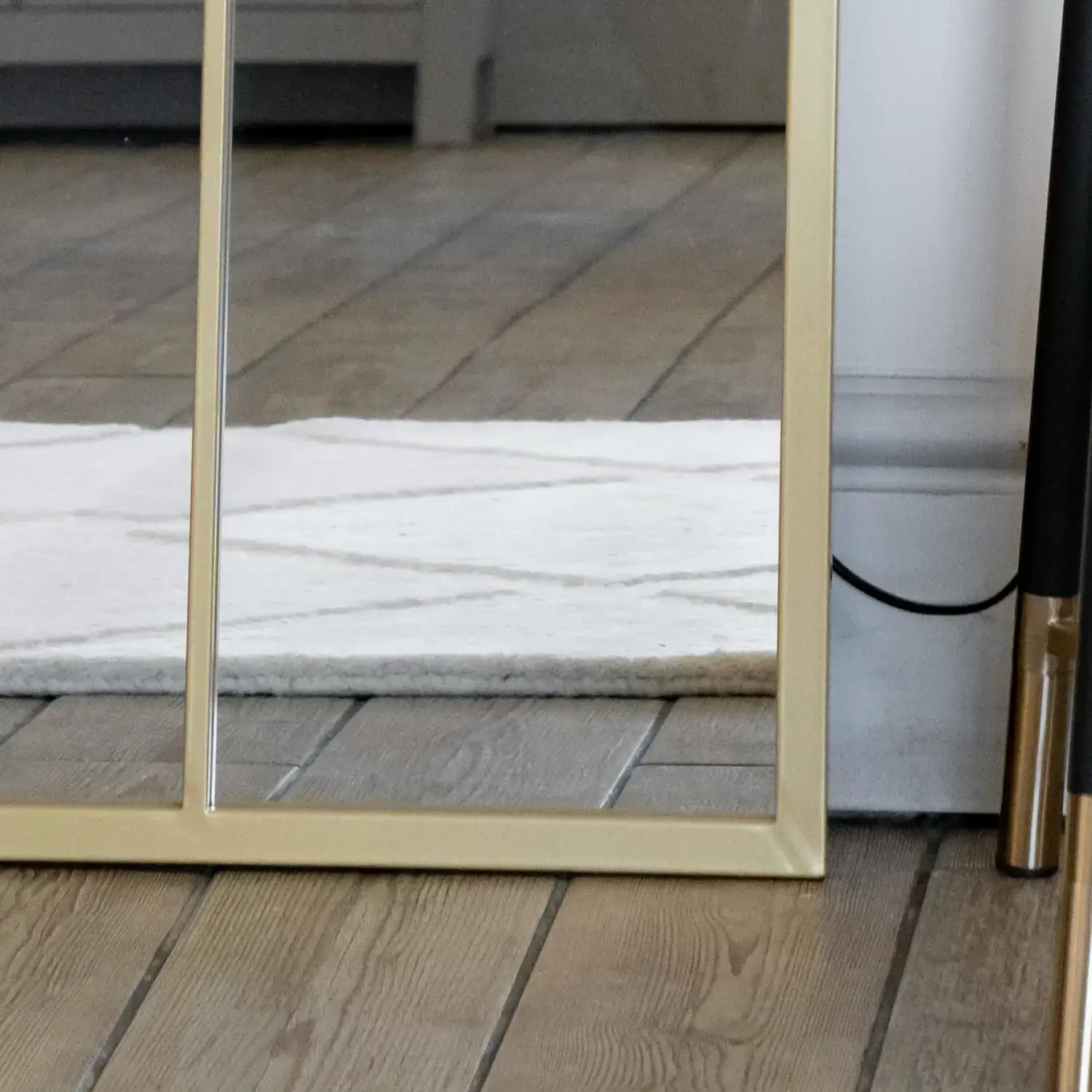 Bottom detail of arched gold lattice mirror — metal frame with soft antique finish and windowpane design
