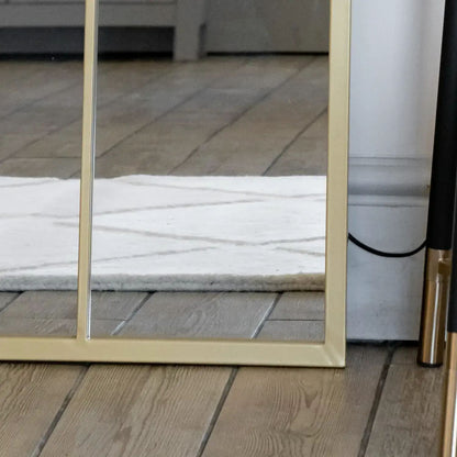 Bottom detail of arched gold lattice mirror — metal frame with soft antique finish and windowpane design