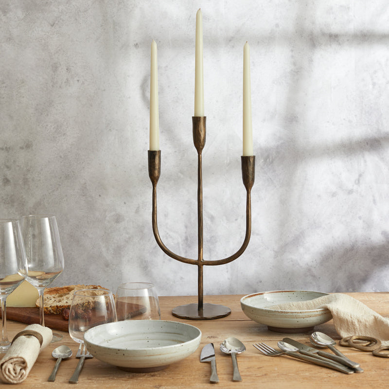 Weldon gold iron trident candelabra with three taper candles on  farmhouse dining table