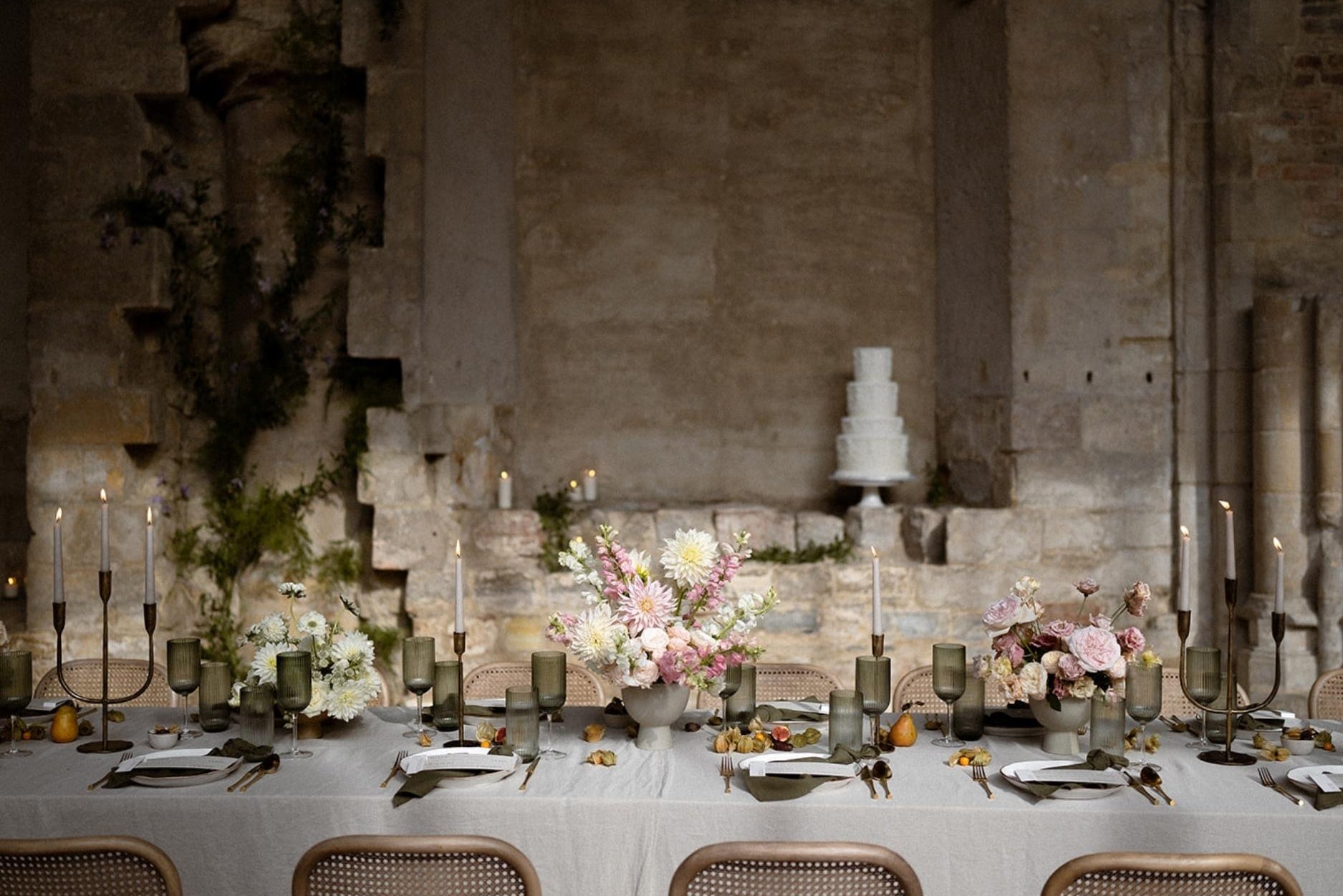 Weldon gold iron trident candelabra with three taper candles, glowing centerpiece on a formal dinner table