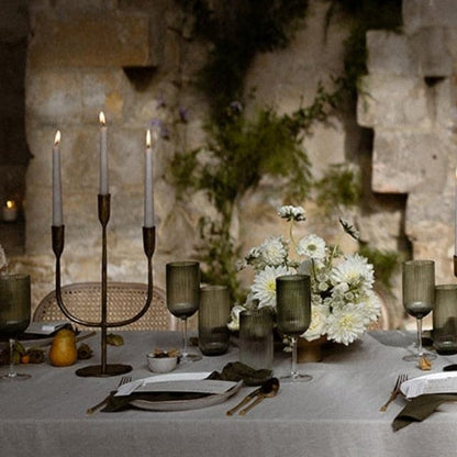 Elegant wedding reception with a long table set for dinner, floral arrangements, and a cake against a stone wall.