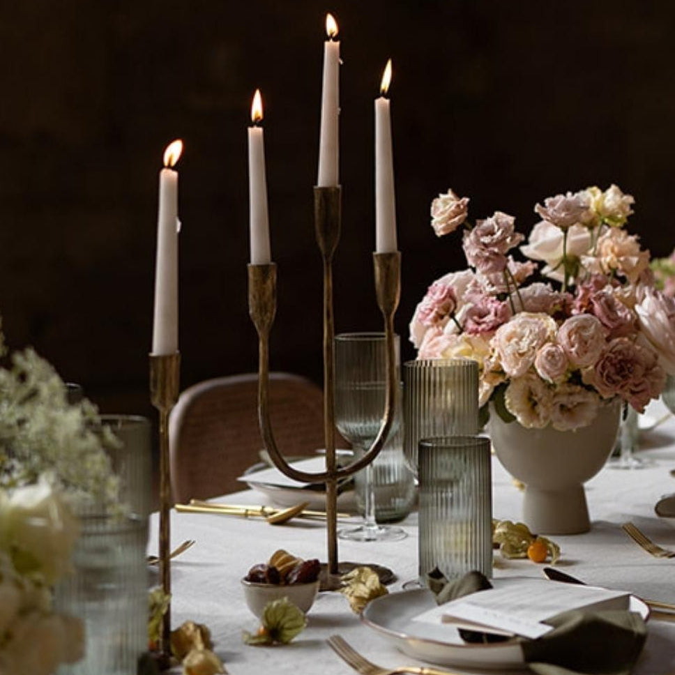 Elegant table setting with candles, flowers, and cutlery on a dark background